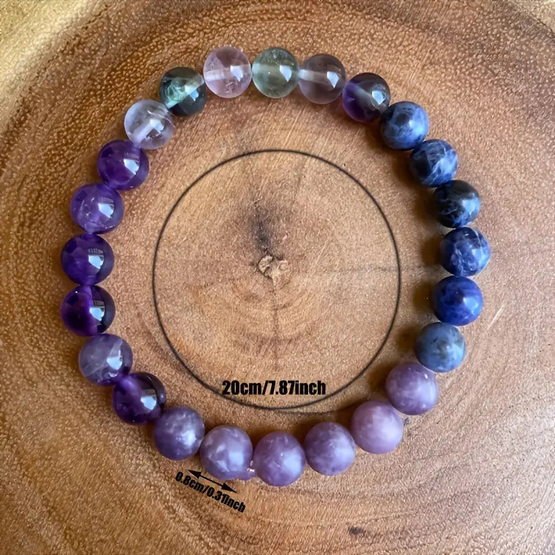 A multicolor gradient fluorite beaded bracelet with crystal accent featuring faceted beads in purple blue and green hues arranged in a circular pattern.