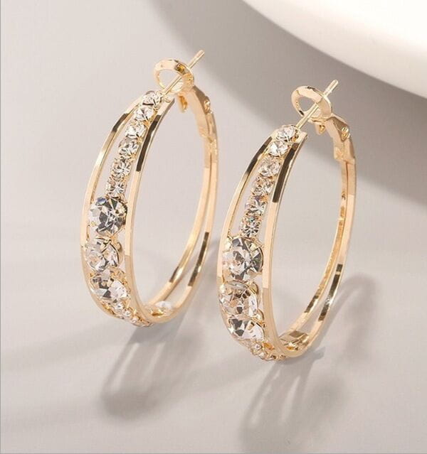 Boucles d’oreilles créoles en or pour femmes, ornées de cristaux transparents étincelants incrustés le long de la courbe géométrique.