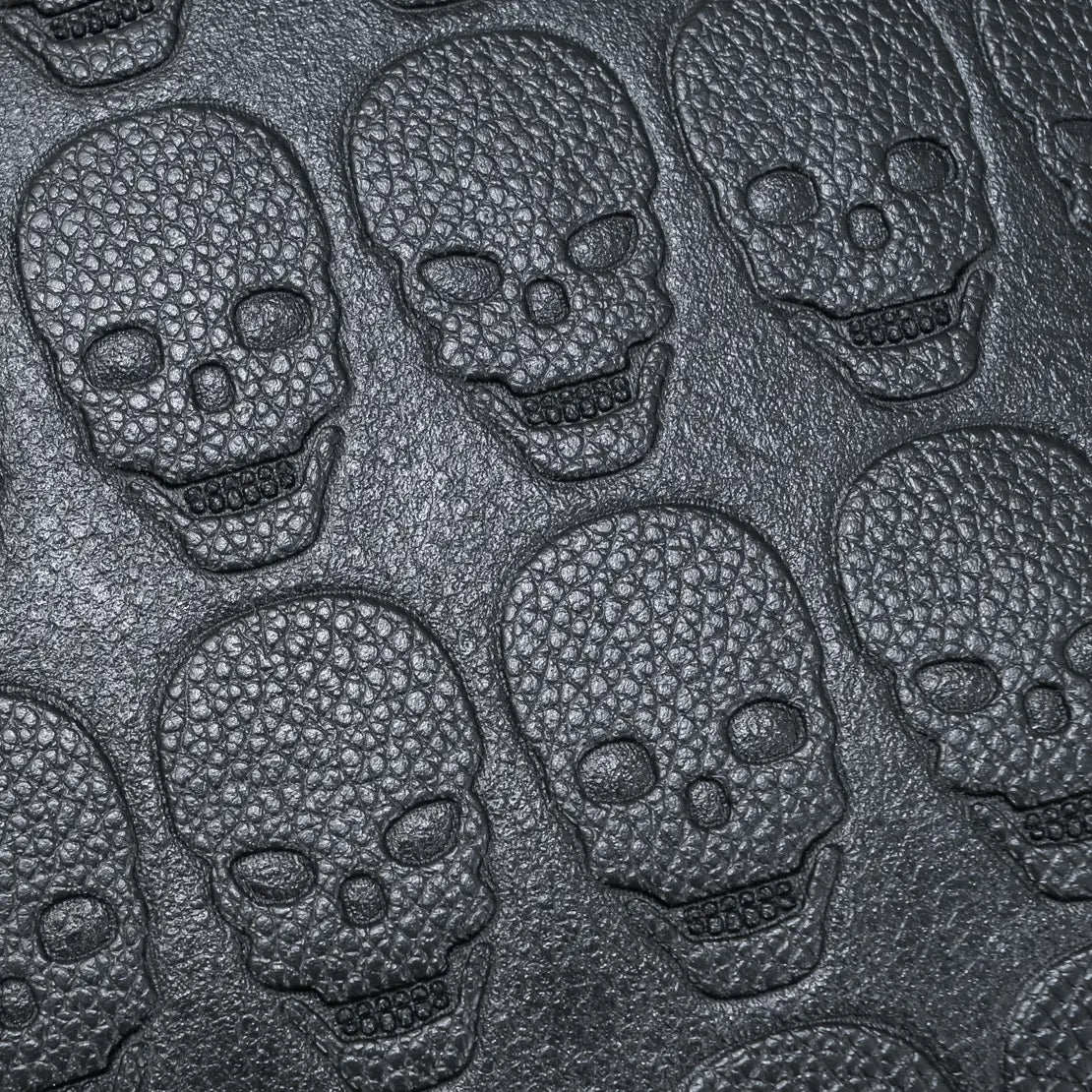 black studded skull leather commute backpack featuring black textured leather with embossed skull patterns