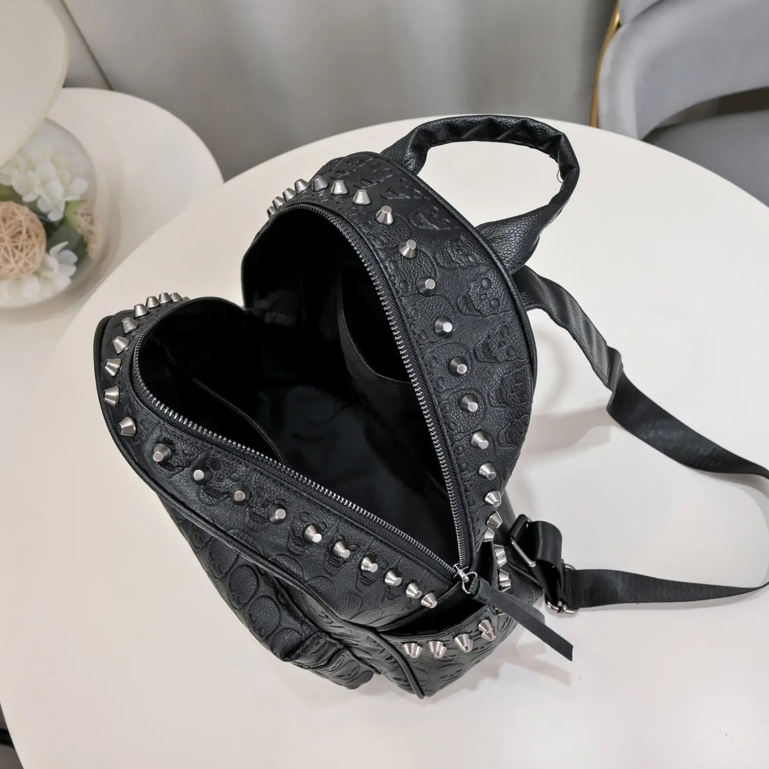 Black studded skull leather commute backpack made of leather-like material featuring an embossed skull pattern.