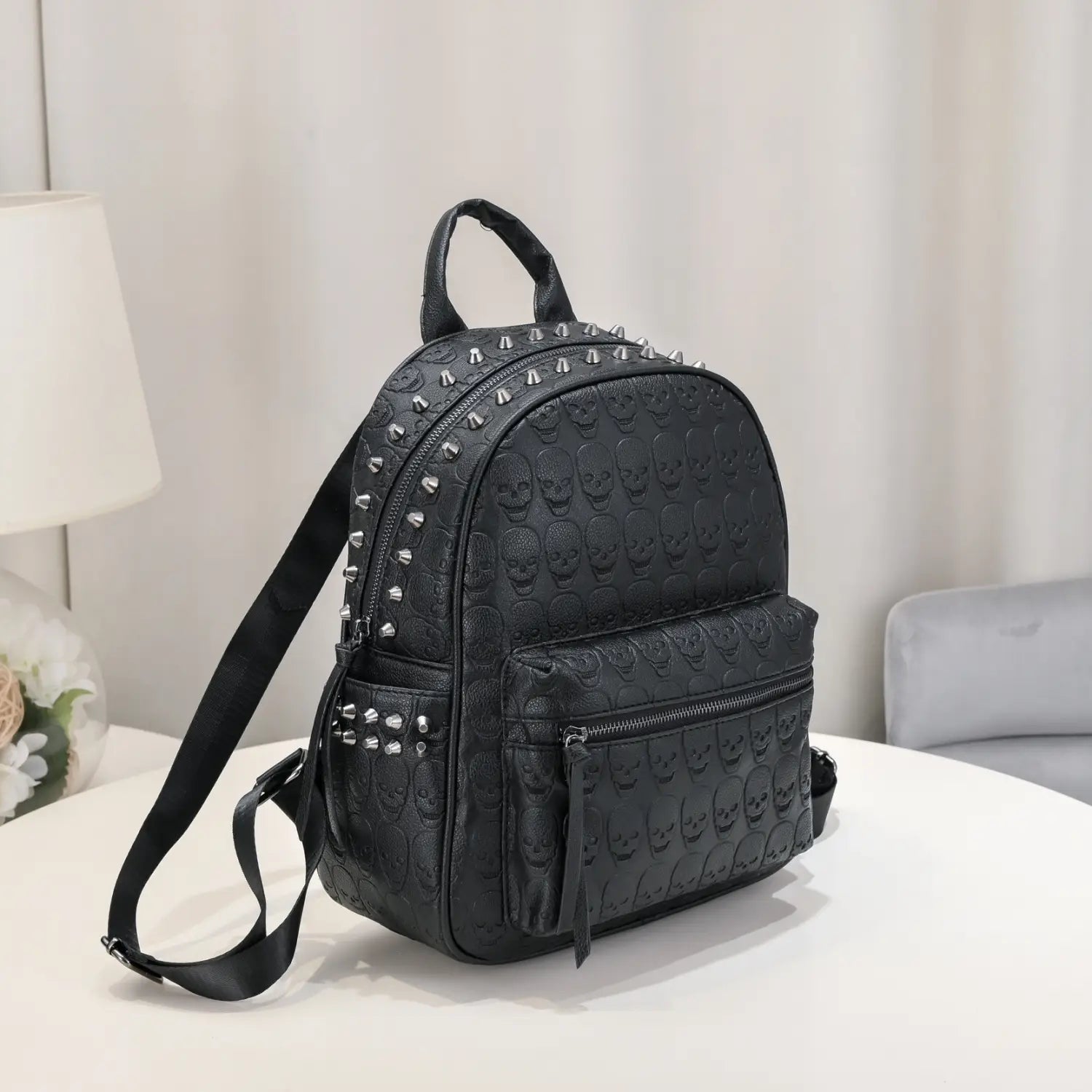 Black studded skull leather commute backpack featuring silver studs and zippers on a black skull-patterned design.