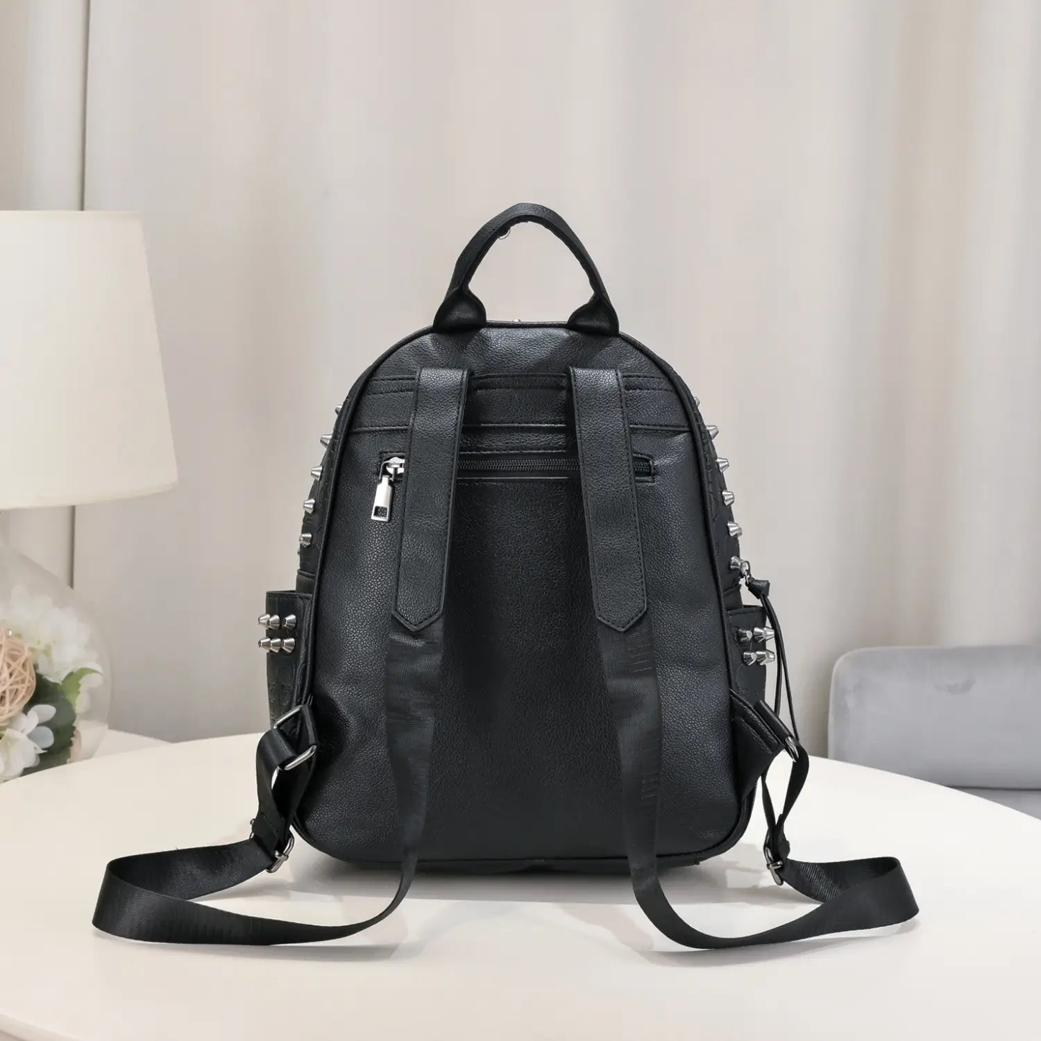 black studded skull leather commute backpack in black faux leather with silver studs and zipper details