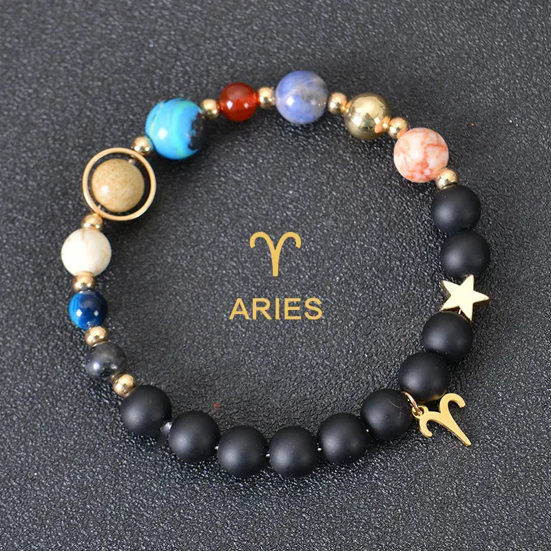A black matte stone beaded bracelet featuring colorful gemstone planets and a gold Aries zodiac charm from the celestial zodiac planet collection.