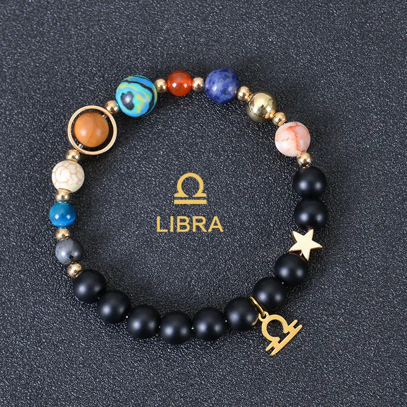 Celestial zodiac planet matte stone beaded bracelet featuring black matte beads with colorful blue orange and pink gemstone accents and gold-toned metal charms including a star and the libra zodiac symbol.