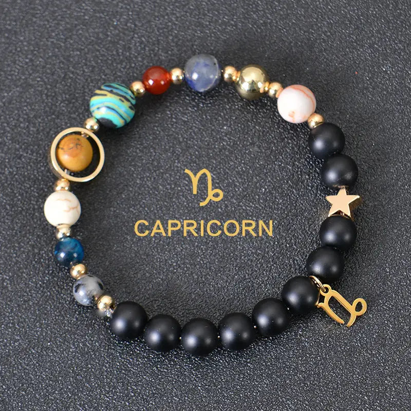 Capricorn zodiac bracelet featuring black matte beads with colorful planet-like stones in blue red gold and white accented by a golden star charm and a metallic Capricorn symbol pendant.