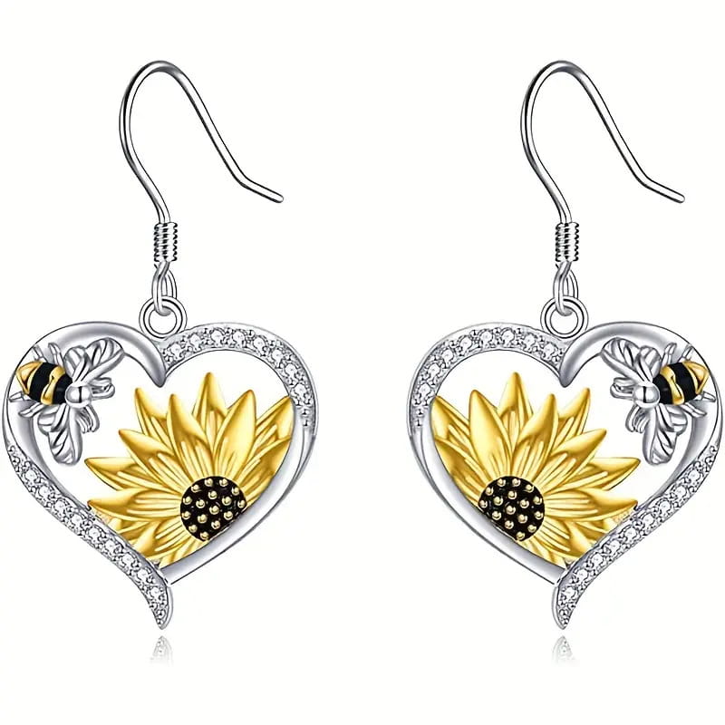 Silberne herzförmige Ohrringe mit einer goldenen Sonnenblume sowie einem Schwarz-Gelb-Bienenmotiv, akzentuiert mit klaren Strasssteinen entlang der Umrandung.