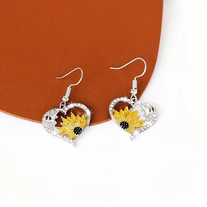 Silberne herzförmige Ohrringe mit einer leuchtend gelben Sonnenblume mit schwarzem Zentrum und Strassstein-Akzenten aus der Kollektion „Bienen- und Sonnenblumen-Herz-Strassstein-Silberohrringe“.