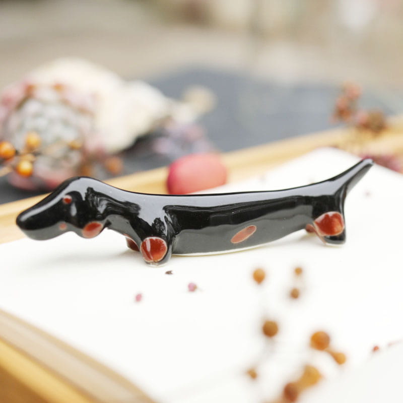 Dackel-Figurenhalter aus schwarzer Keramik mit glänzender Oberfläche und rötlich-braunen Akzenten an Pfoten, Augen und Seite, aus einem Set von vier.