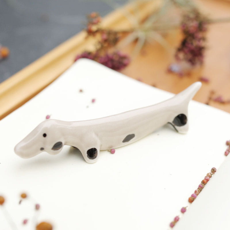 Zierlicher Stäbchenhalter aus weißer Keramik in Form eines Dackels mit glänzenden schwarzen Punkten und dezenten rosa Akzenten, aus einem Set von vier.