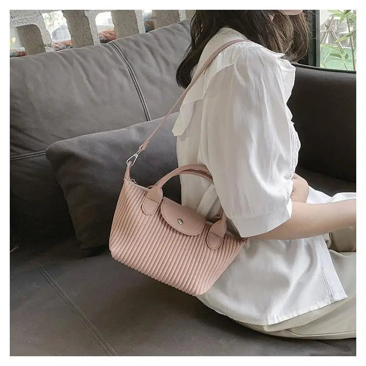 A soft pink ribbed minimalist pu leather tote pleated shoulder bag with a matching top handle and adjustable shoulder strap.