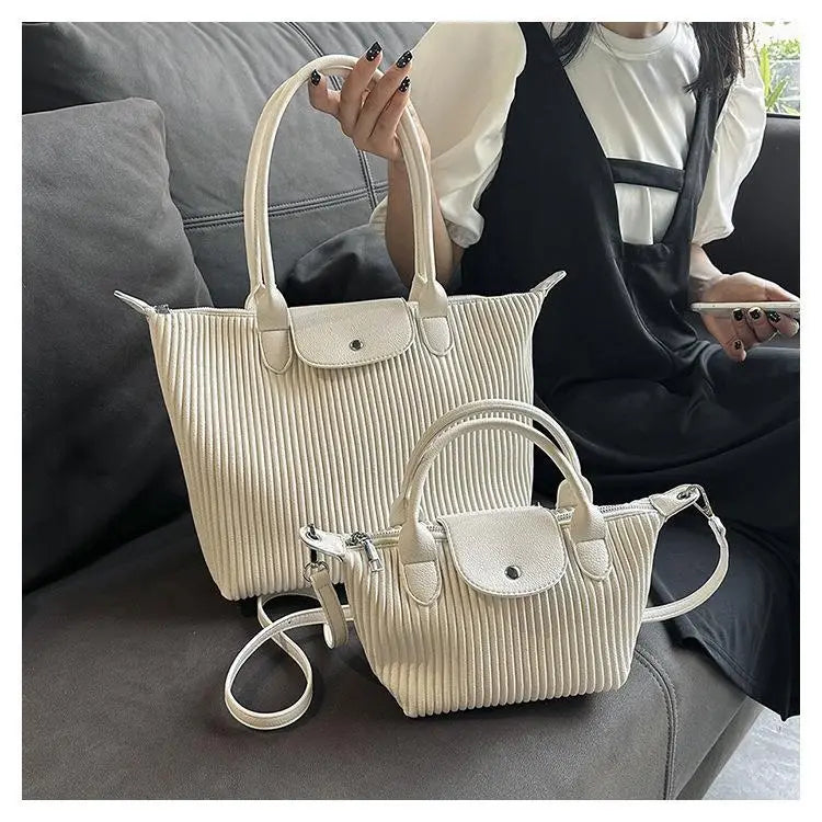 Cream-colored ribbed leather minimalist pleated shoulder tote and crossbody bags with matching top flaps.
