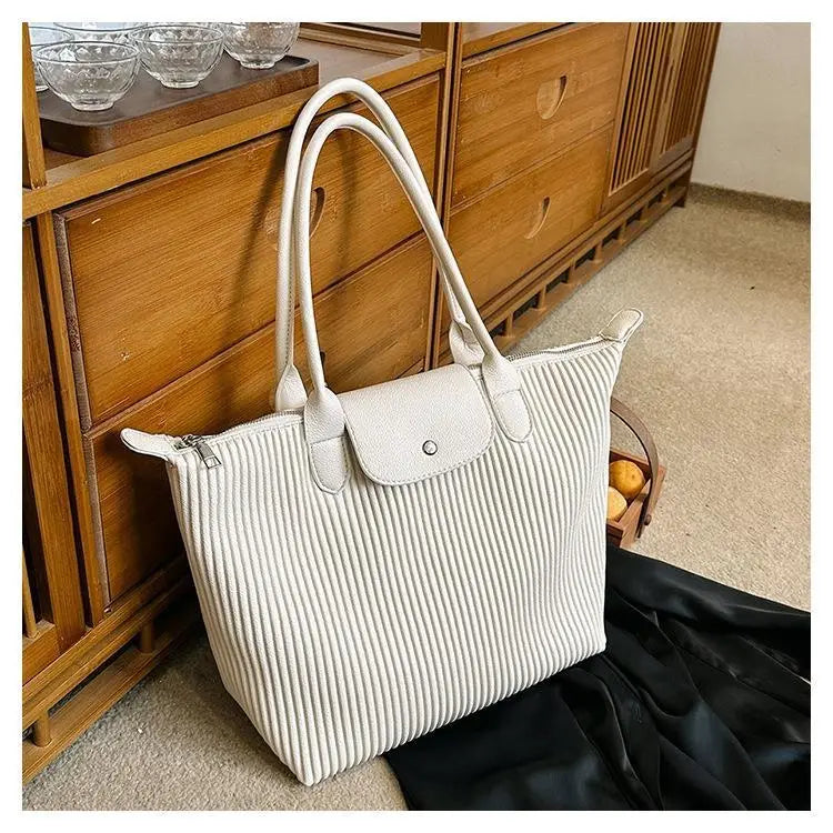 A white pleated leather tote bag with a flap closure and matching handles designed as a minimalist Pu leather shoulder tote.