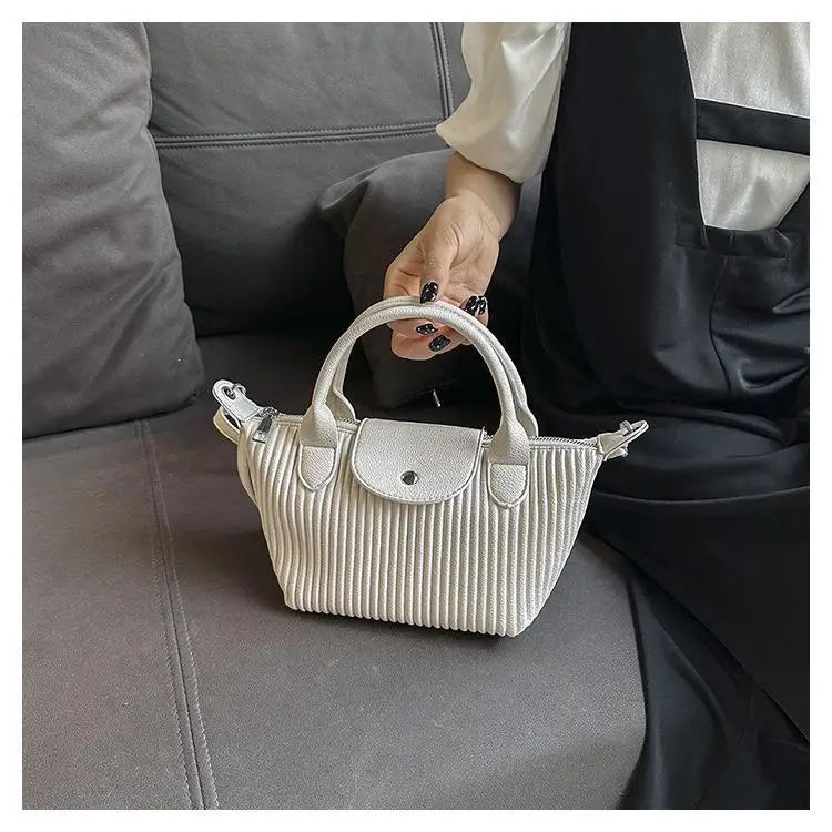 A white ribbed leather pleated shoulder bag with a fold-over flap and top handles made of minimalist pu leather tote.