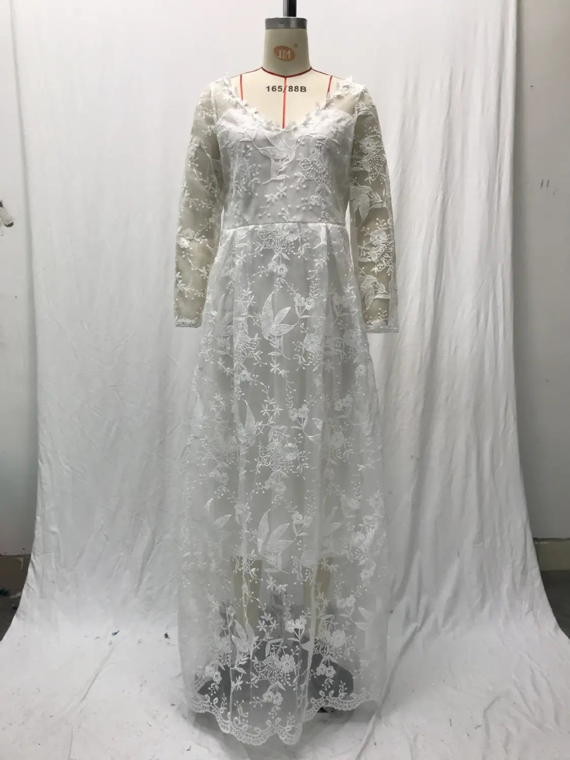 Off shoulder lace long sleeve bridal wedding gown in white with delicate floral embroidery displayed on a mannequin.