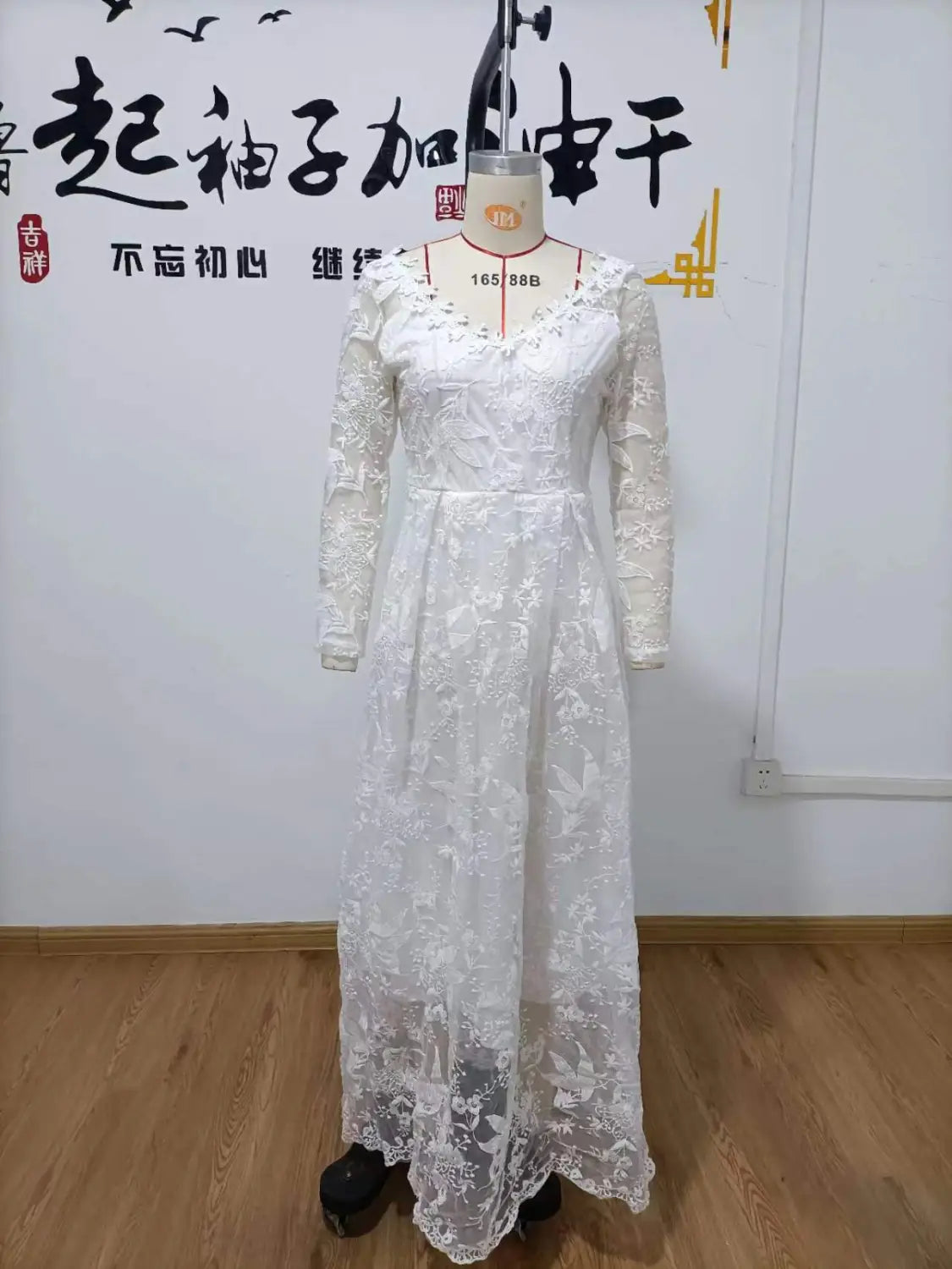 Off shoulder lace long sleeve bridal wedding gown in white with intricate floral patterns and a fitted waistline.