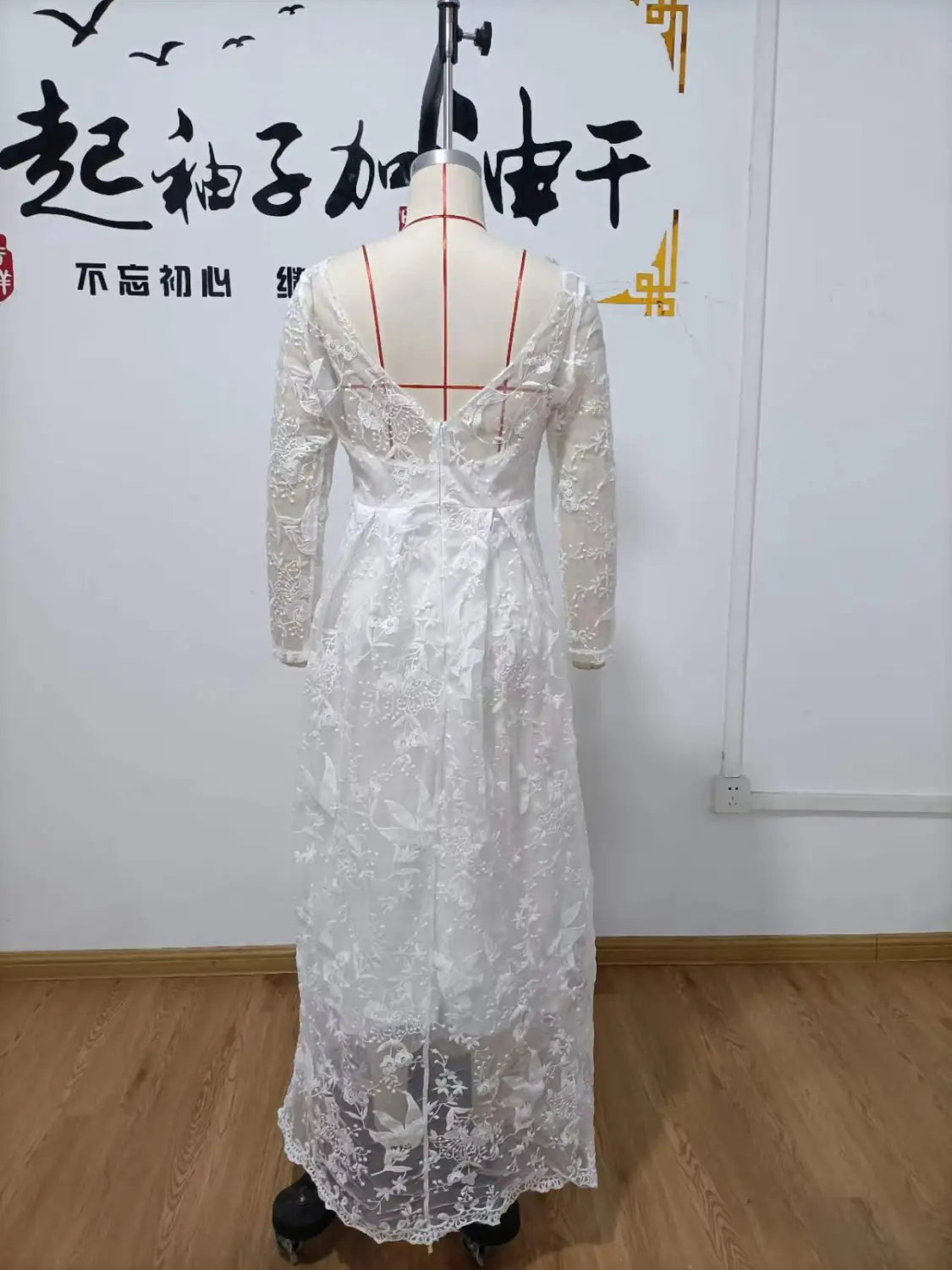 A long white off shoulder lace bridal wedding gown with long sleeves and intricate floral patterns shown from the back with a deep v-back design.