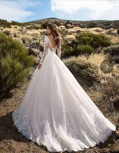 off shoulder lace long sleeve bridal wedding gown in flowing white lace with long sleeves and a deep back neckline shown from the back side