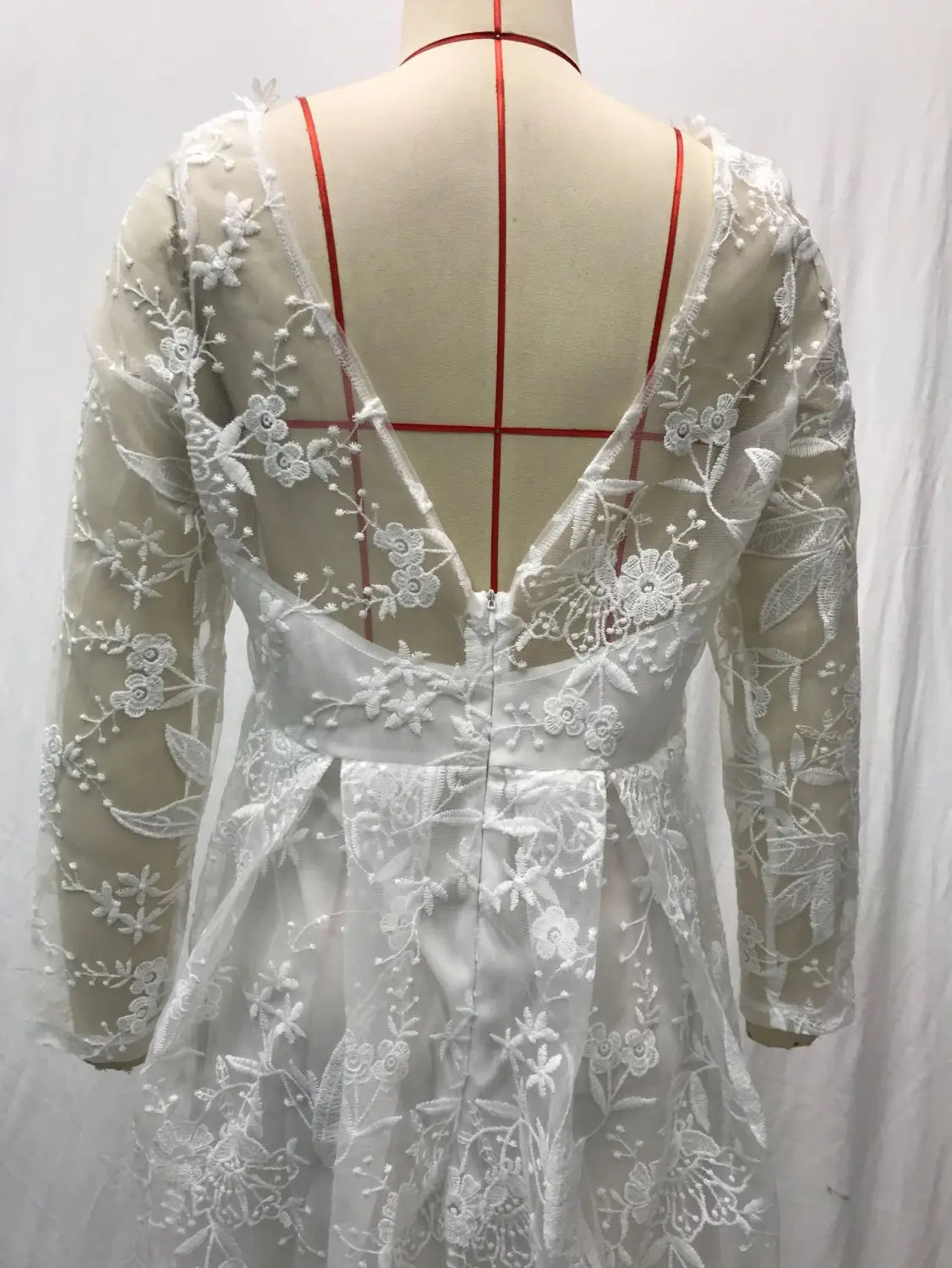 A delicate white off shoulder lace bridal wedding gown with long sleeves and a deep v-back featuring intricate floral embroidery on the back.
