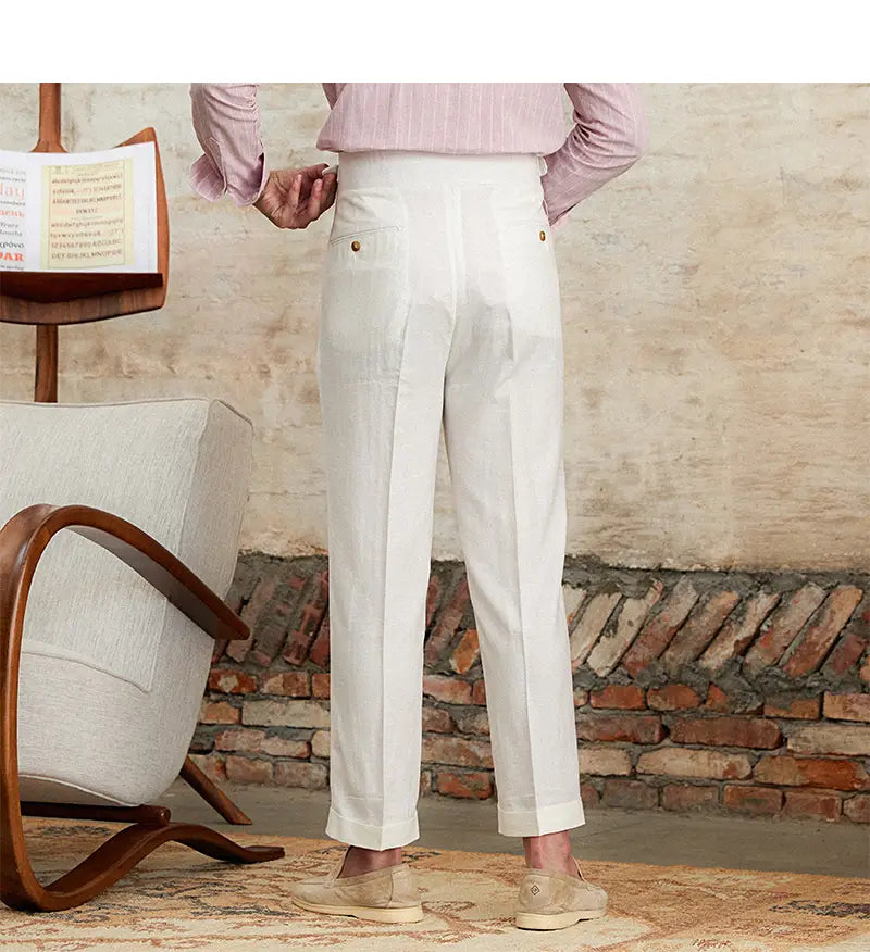Pantalons blancs en lin et coton à taille haute, coupe droite plissée, présentés de dos, avec des détails de boutons ton or sur les poches.