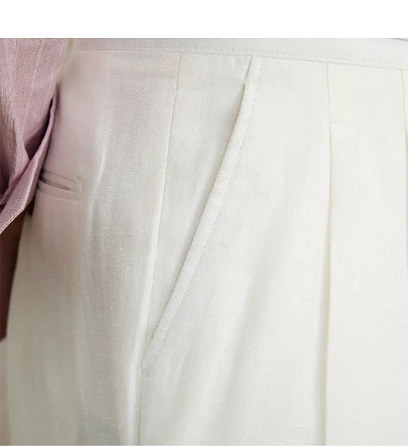 Pantalons blancs en lin et coton à taille haute, coupe droite plissée, avec un tissage texturé subtil.