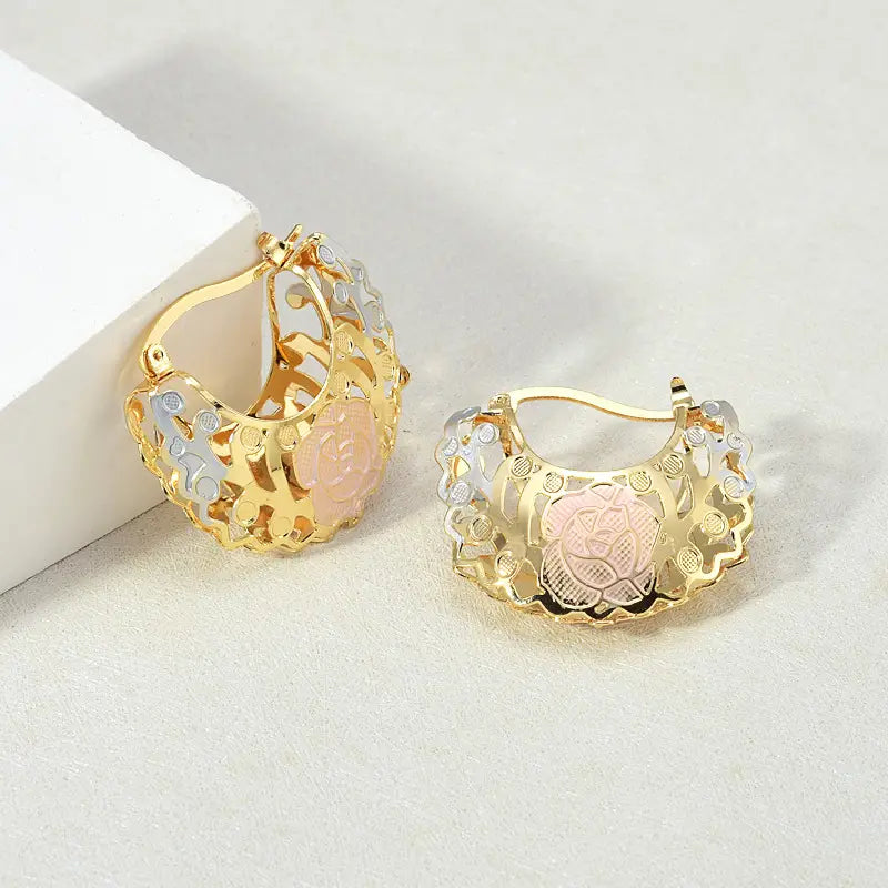 Two tone rose motif hoop earrings featuring gold and silver floral filigree designs with a central pink enamel rose stone.