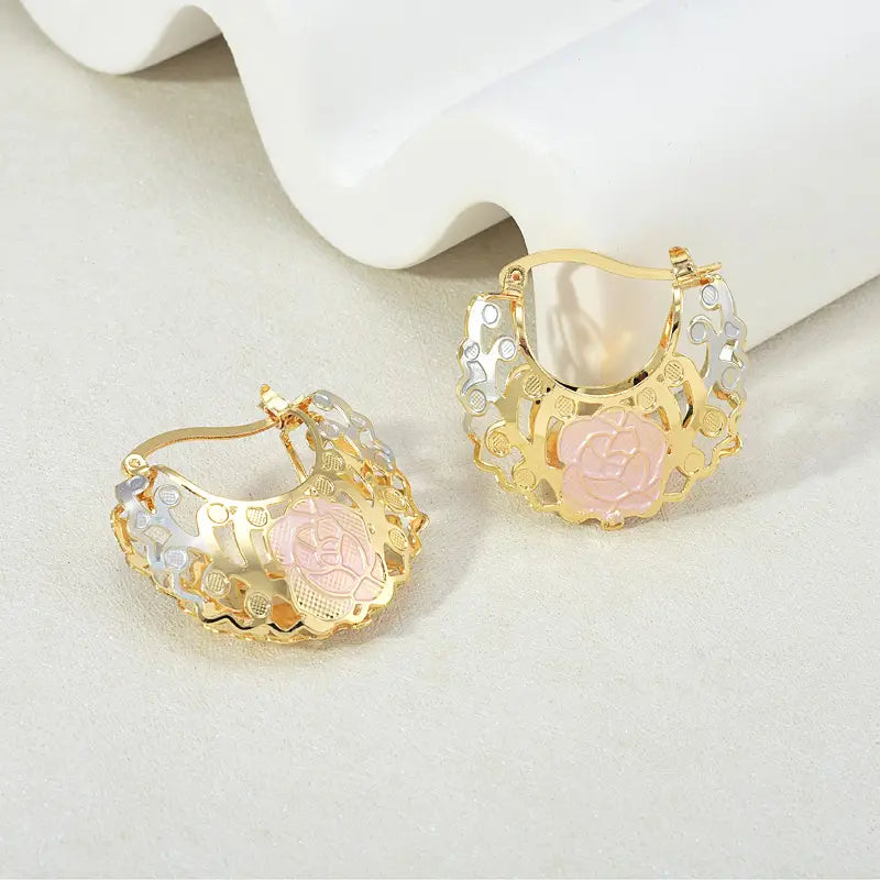 Gold and silver two tone hoop earrings featuring delicate rose designs with pink enamel accents.