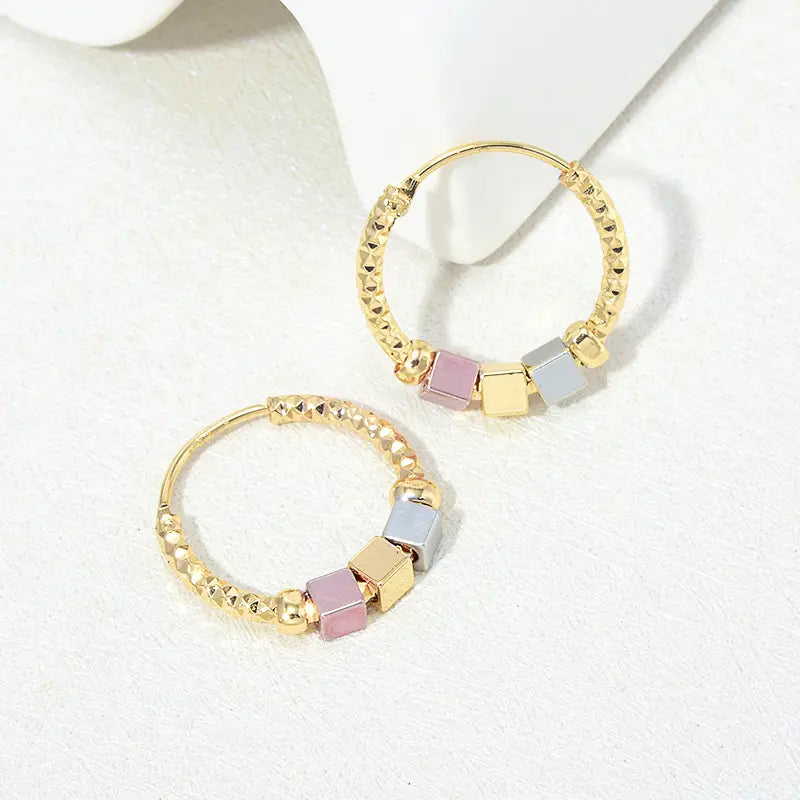 Gold-toned two tone rose motif hoop earrings featuring a textured beaded design with pink, gold, and silver square beads and pink enamel accents.