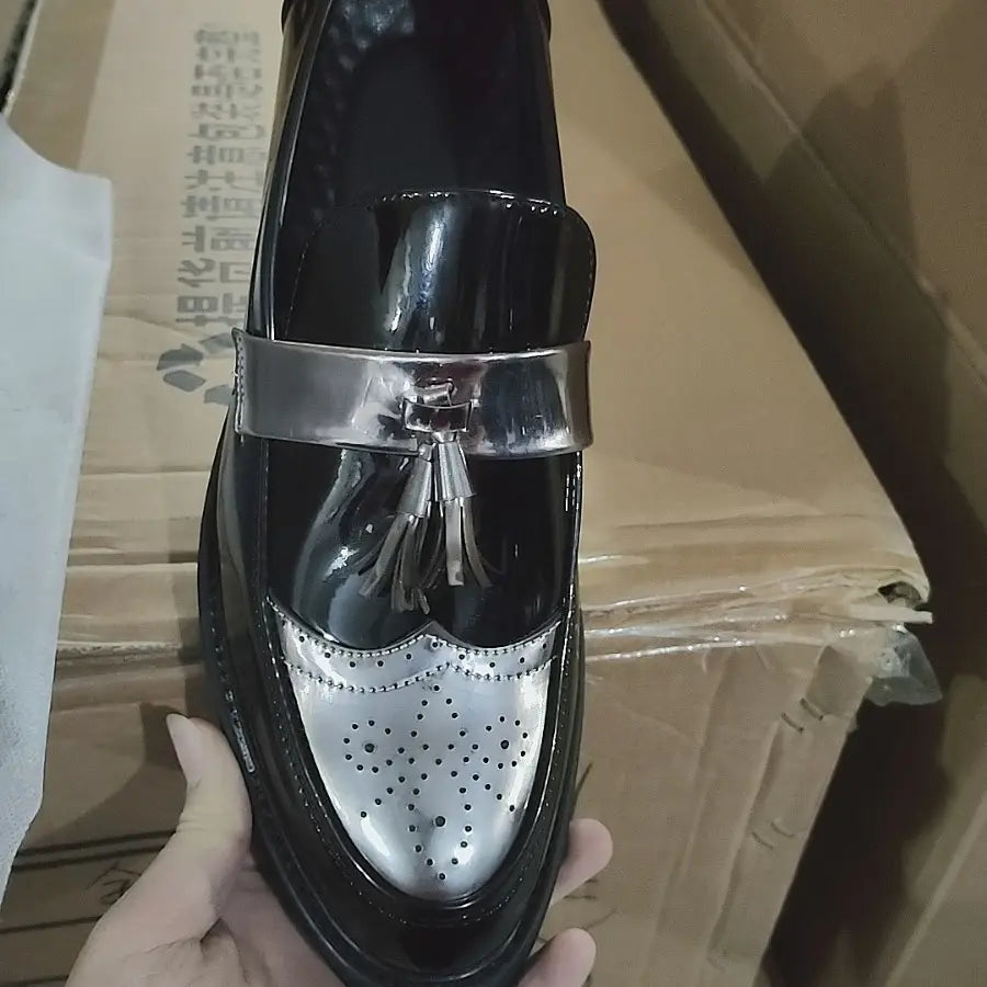 Schwarzer Herren-Slipper aus Lackleder mit Quasten, mit silberfarbenem Metallriemen und perforierter Kappe.