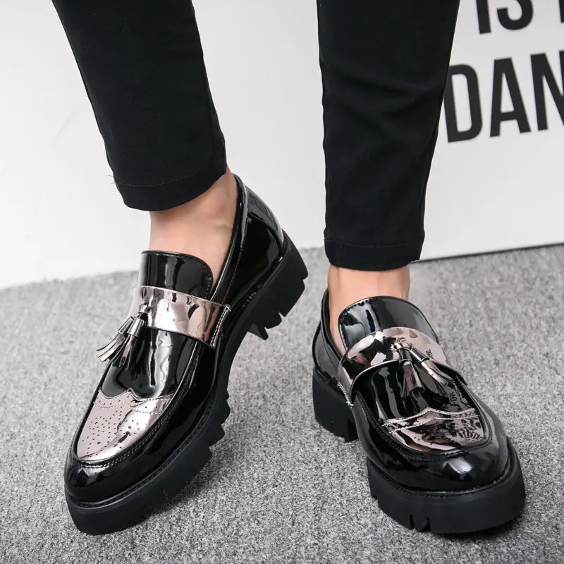 Herren-Slipper aus schwarzem Lackleder mit silberfarbenen Metallriemen und Quasten-Details.