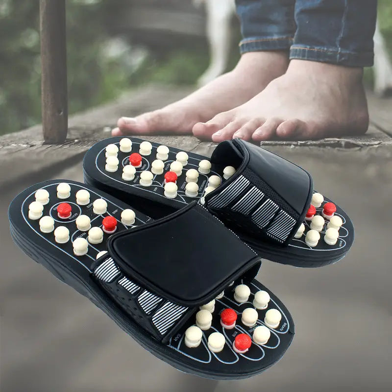 Acupressure massage slippers for men and women in black featuring white and red acupressure beads arranged in rows on the soles.