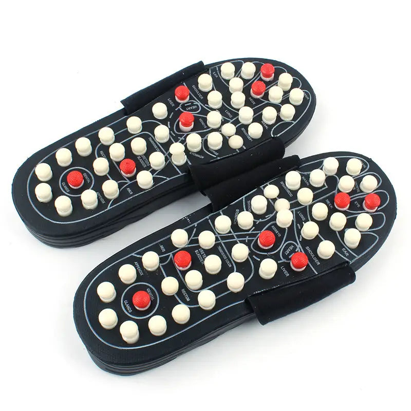 Black acupressure massage slippers for men and women featuring white and red acupressure points arranged in a pattern over the soles.