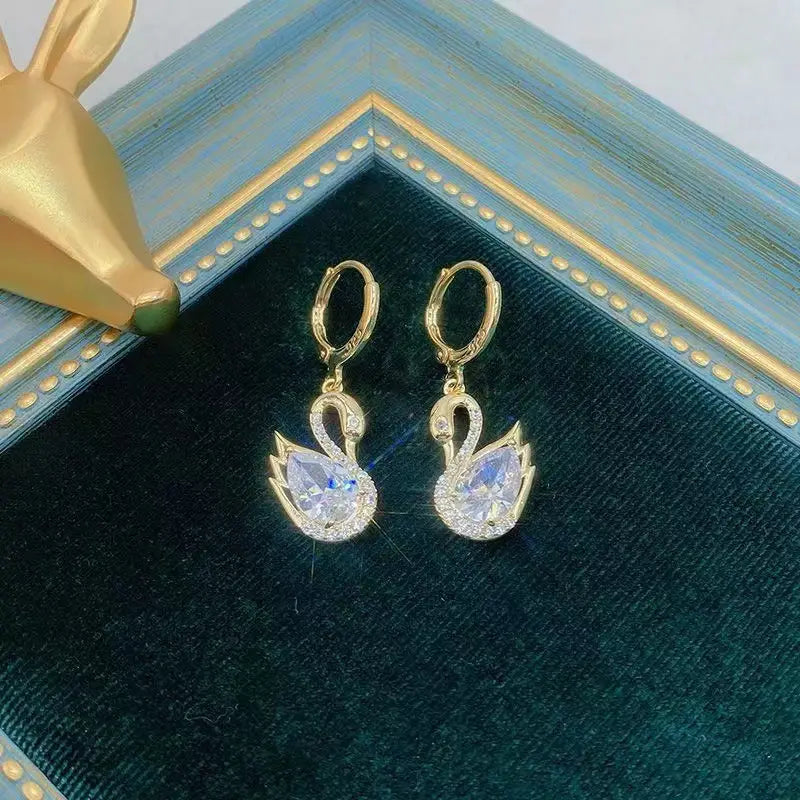 Gold-toned swan drop earrings for women featuring a central clear crystal surrounded by smaller sparkling rhinestones.