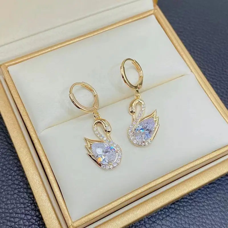 Crystal rhinestone swan drop earrings for women in gold tone featuring a central pearlescent crystal surrounded by smaller clear crystals along the outline.