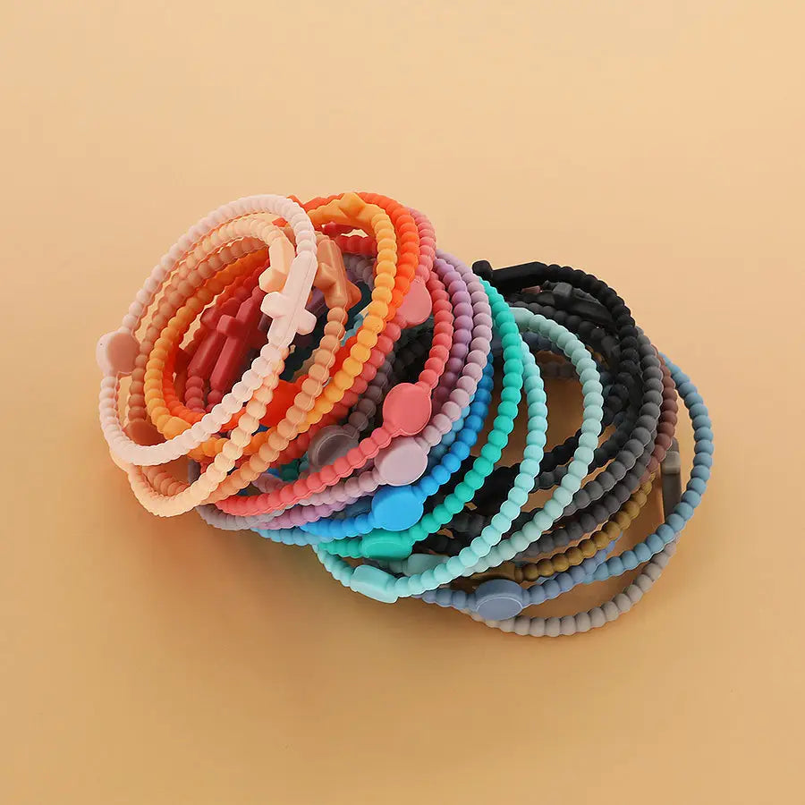 A collection of beaded silicone cross bracelets with round clasps in assorted pastel and vibrant colors featuring decorative cross and circular charms.