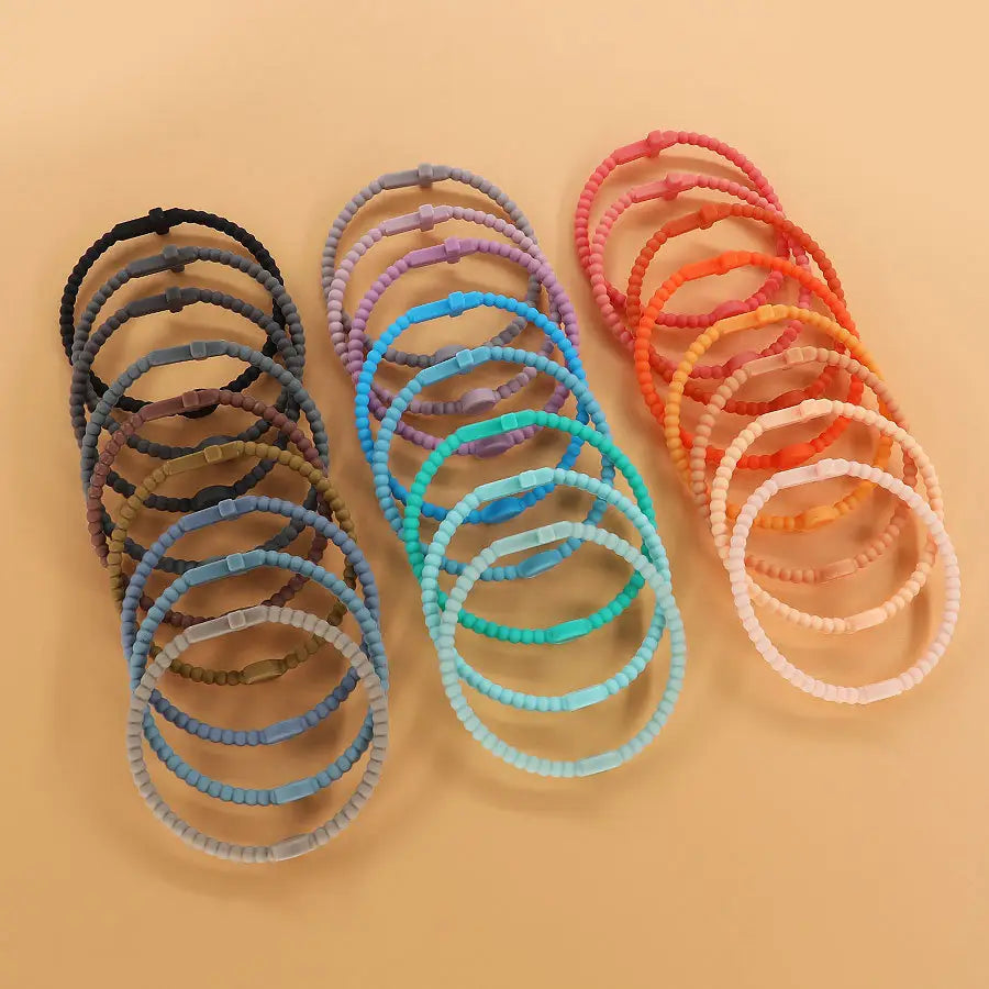 a collection of colorful beaded silicone cross bracelets with round clasps in assorted pastel and vibrant hues displayed for fashion use