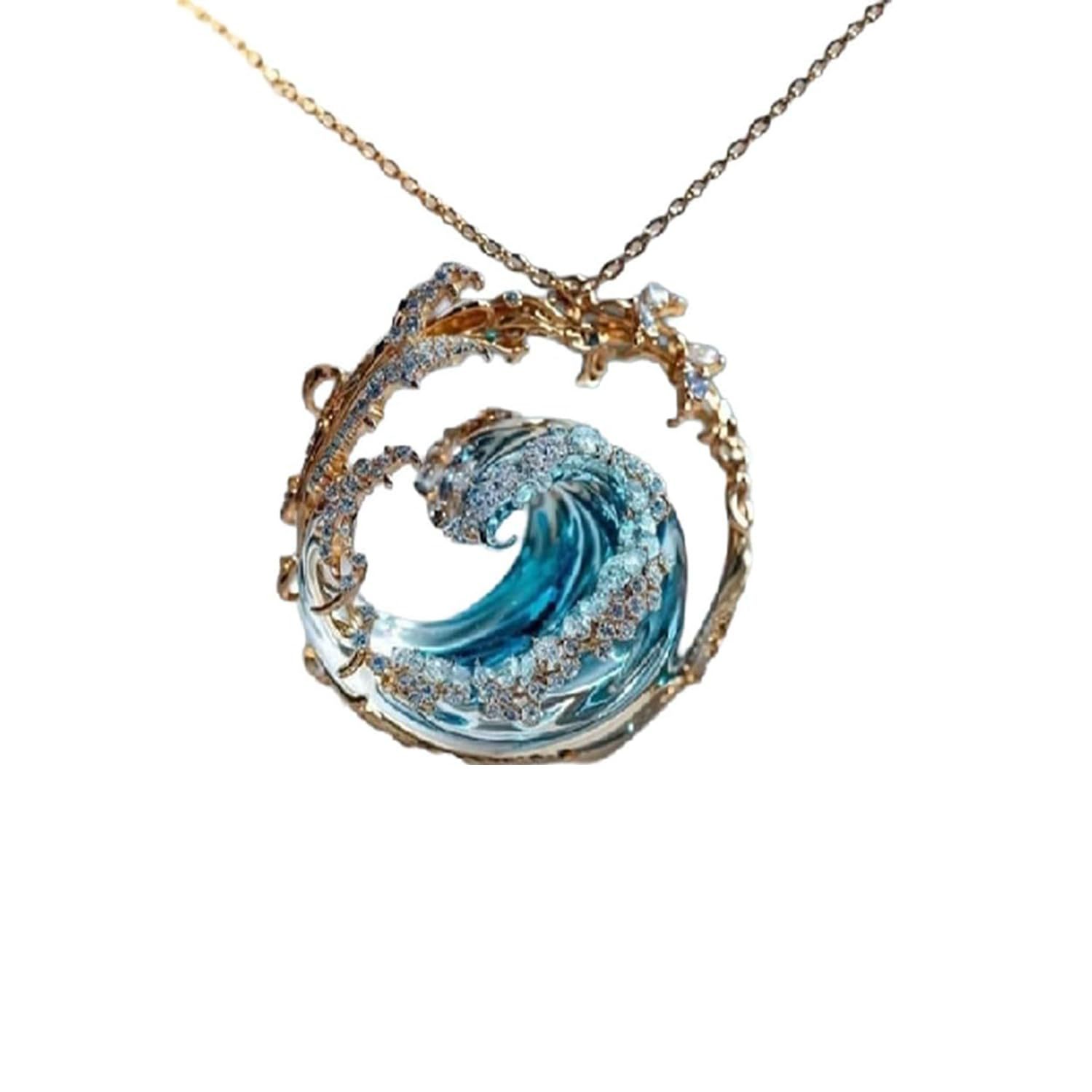 A delicate ocean wave turquoise glass pendant necklace with intricate swirling blue glass encased in gold toned metal and adorned with sparkling clear gemstones.