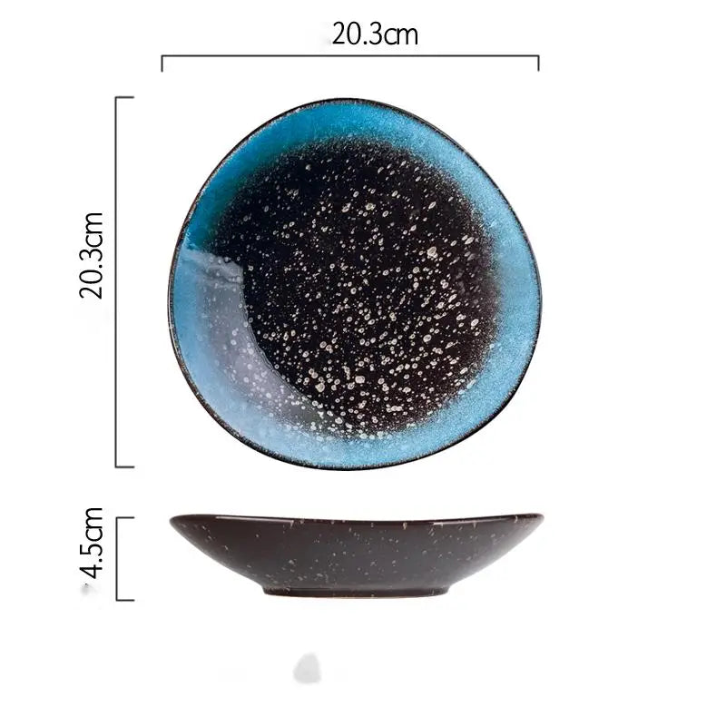A ceramic blue speckled nordic round corner fillet plate with a gradient glaze transitioning from deep blue to black and a glossy finish.