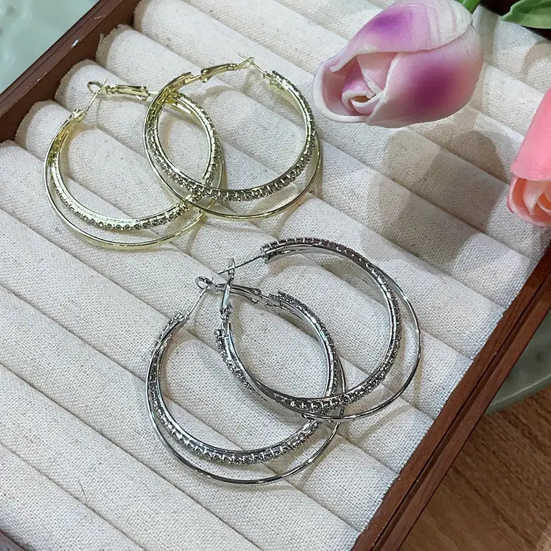 double layered crystal pave hoop earrings featuring gold and silver tones with sparkling rhinestones embellishing the hoops.