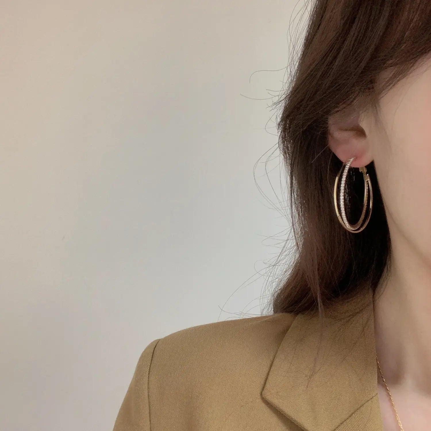 Gold-toned double layered hoop earrings with a delicate sparkling crystal pave edge.
