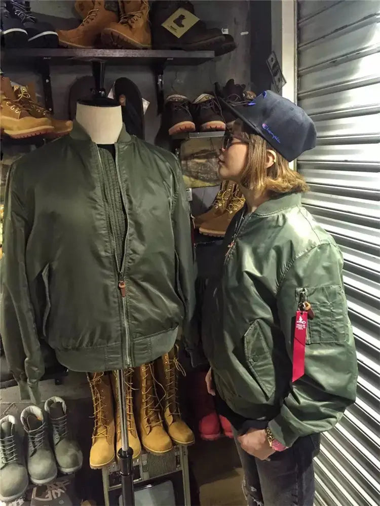 Olive green ma1 pilot bomber jacket with a casual stand collar featuring a red zipper pull and a red tag on the left sleeve.