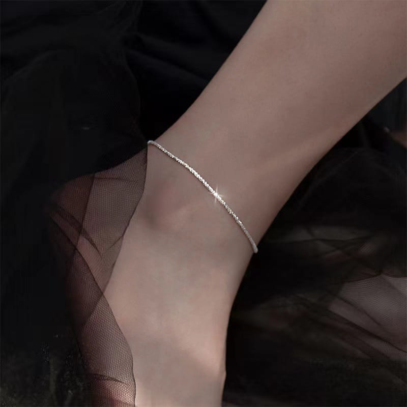 A delicate silver chain anklet with a subtle twisted design elegantly wrapped around the ankle from the adjustable 925 silver sparkling crystal bracelet and anklet set.