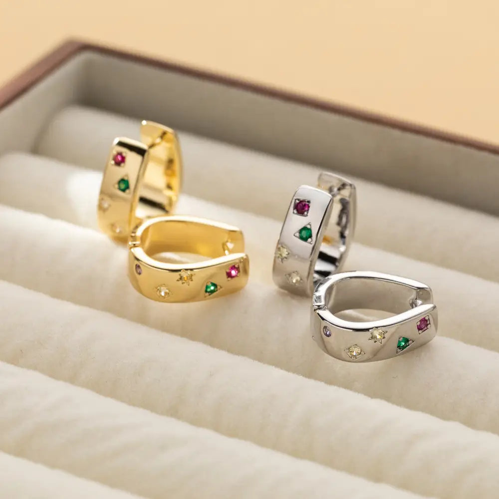 Gold and silver geometric multi color zircon huggie hoop earrings featuring colorful gemstones in a starburst pattern.