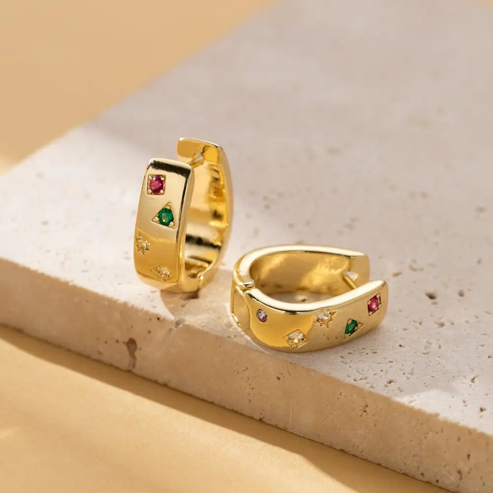 gold-colored geometric multi color zircon huggie hoop earrings adorned with red green and clear star-shaped gemstones