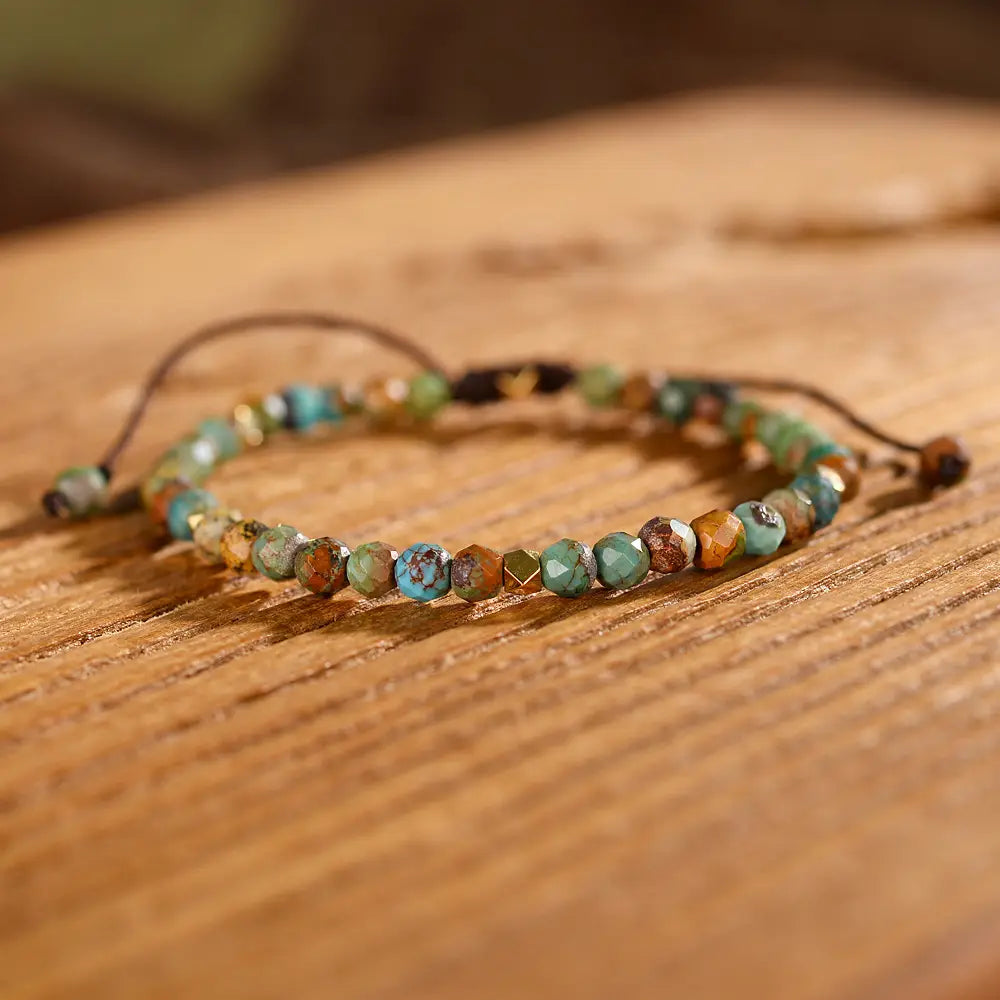 An adjustable African turquoise braided leather bracelet handcrafted with faceted turquoise and earthy brown stones strung on a natural leather cord.