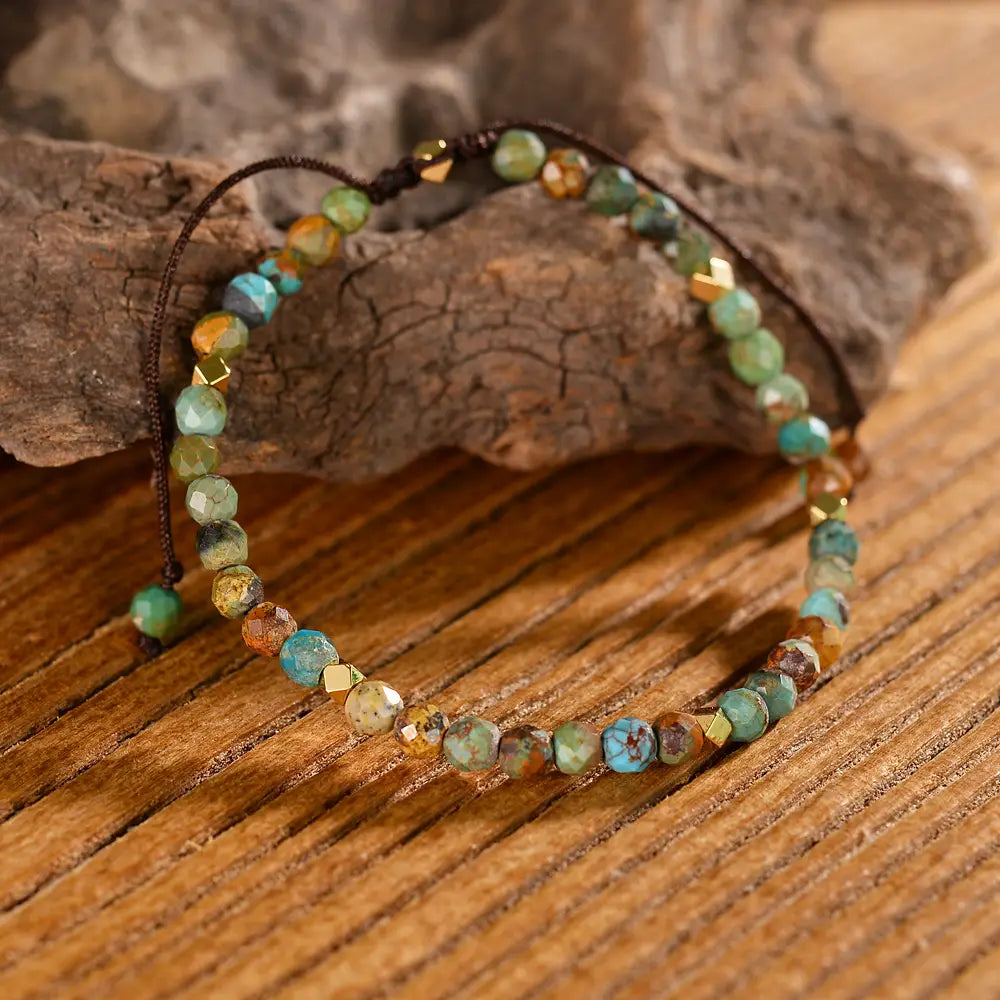 Adjustable African turquoise braided leather bracelet with faceted turquoise and earthy stones accented by small gold-tone geometric beads on a dark brown cord.