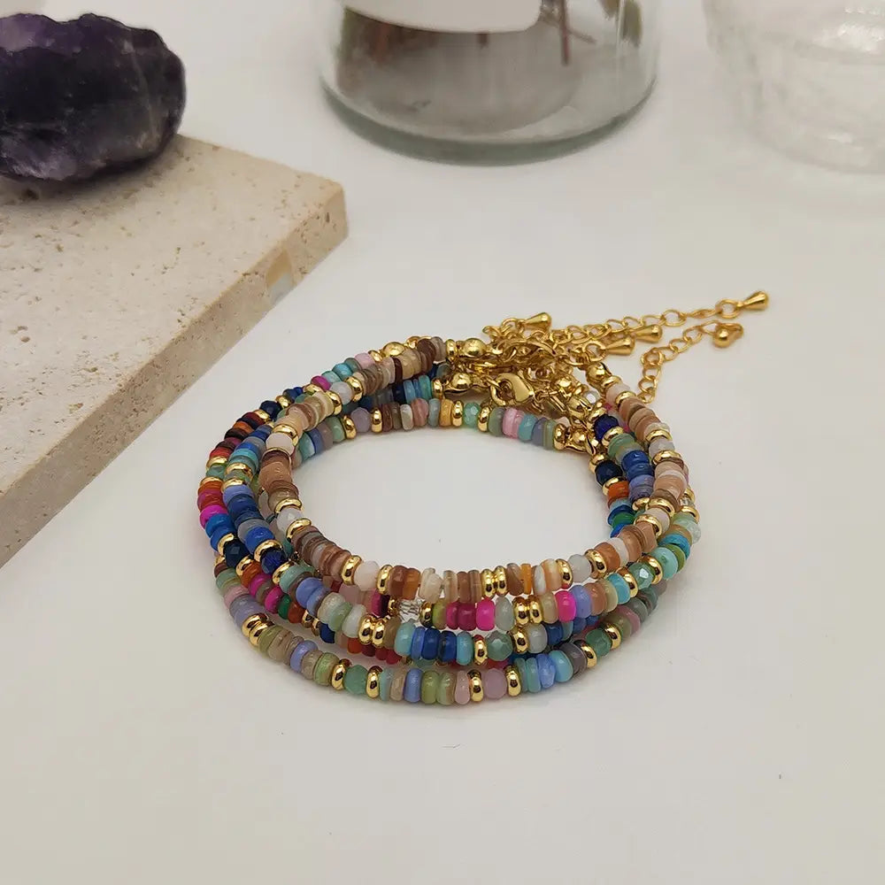 Handwoven rainbow shell beaded bracelet with colorful beads gold-toned metal accents and a chain clasp.