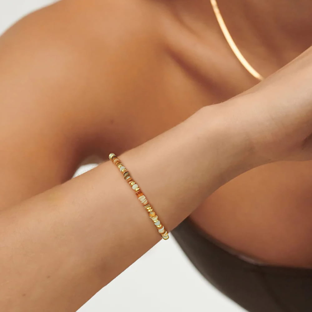 Handwoven rainbow shell beaded bracelet with gold clasp featuring a delicate gold-toned beaded design with alternating round and rectangular beads with subtle shimmer.