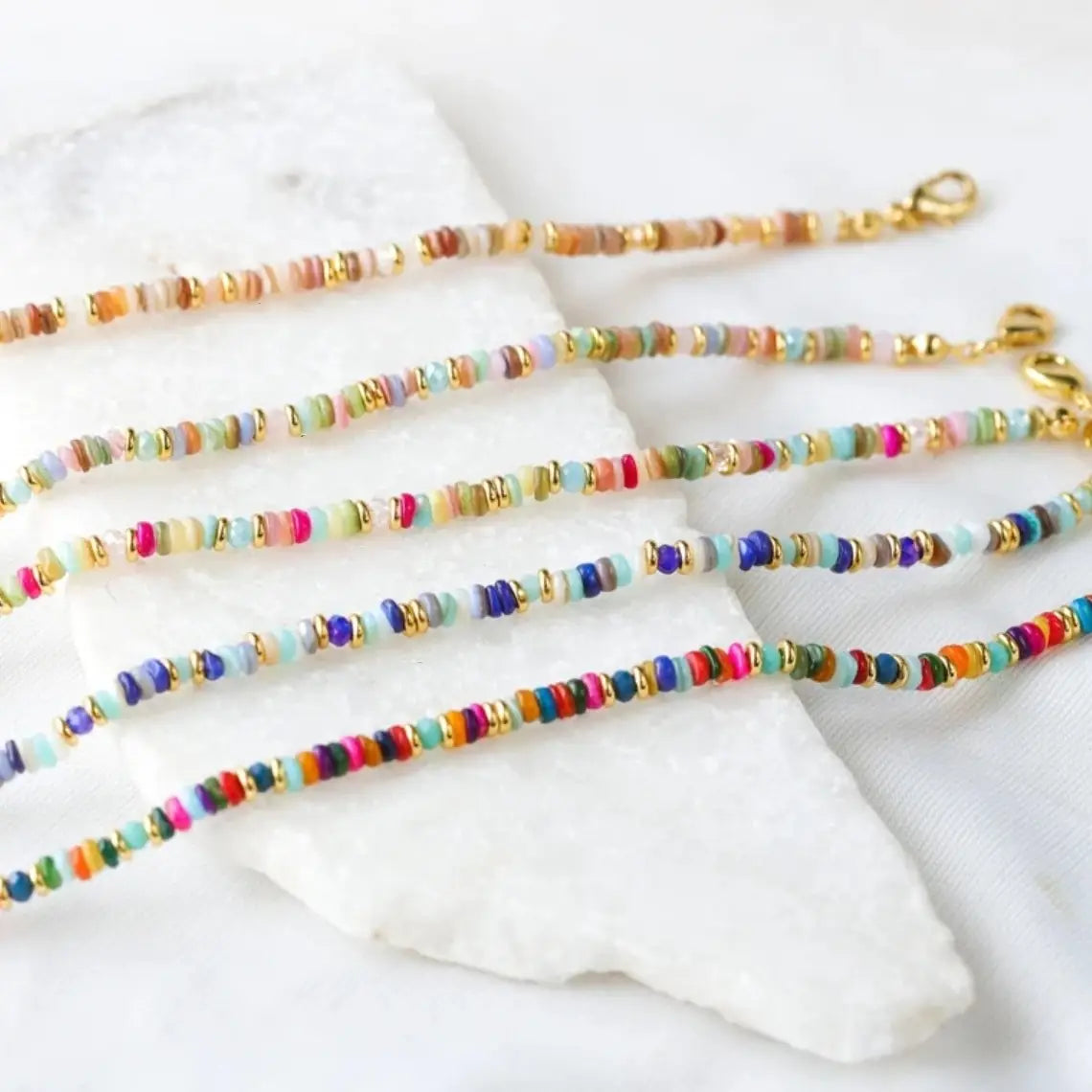 Colorful handwoven rainbow shell beaded anklets with gold-toned clasps designed for stylish wear.