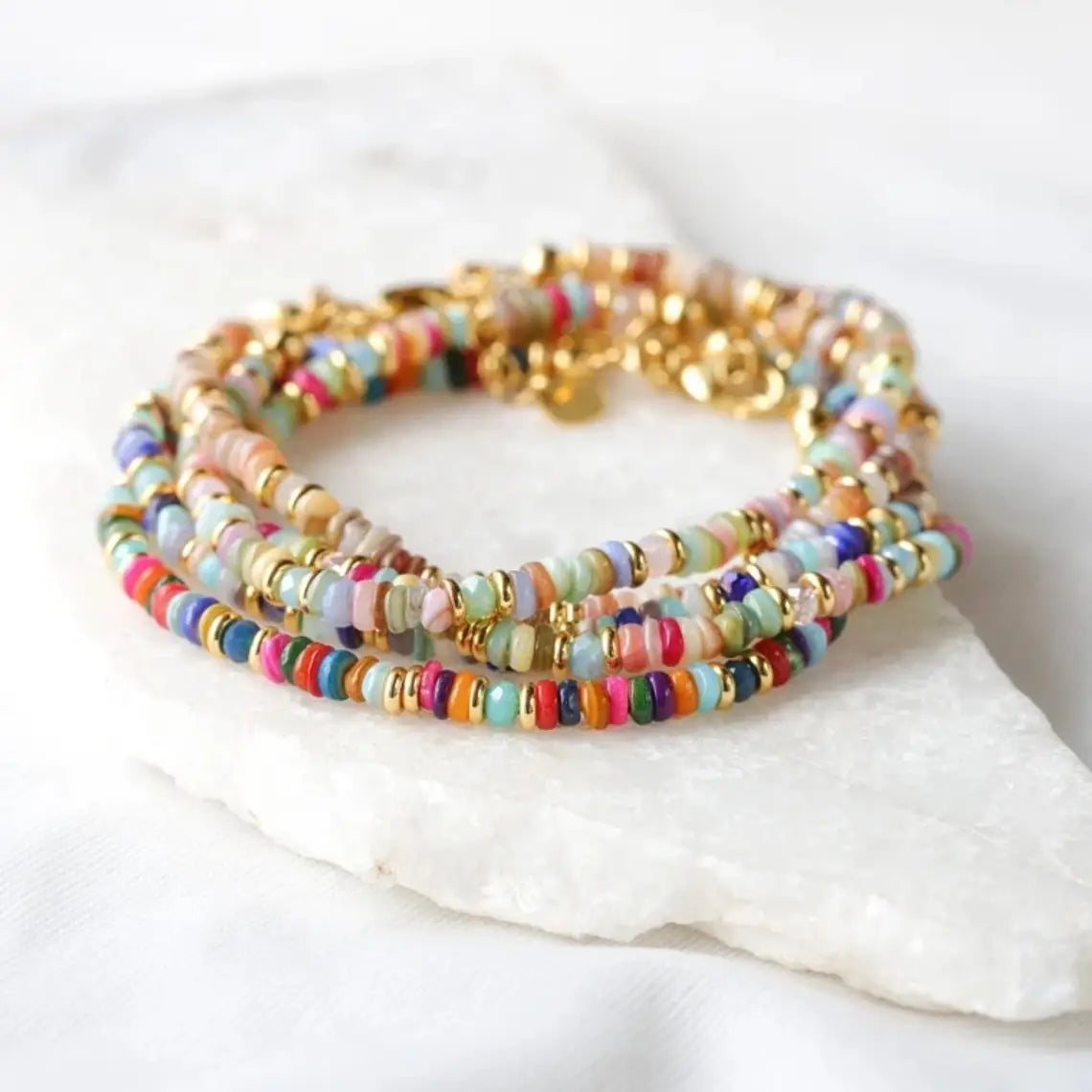 Handwoven rainbow shell beaded bracelet with multicolored round beads and gold-toned metal spacers featuring a gold clasp.