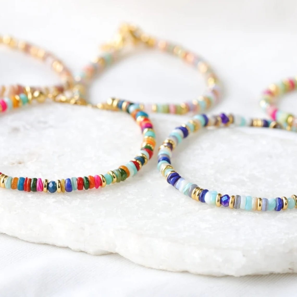 Handwoven rainbow shell beaded bracelet with colorful beads and gold-toned accents featuring a gold clasp.